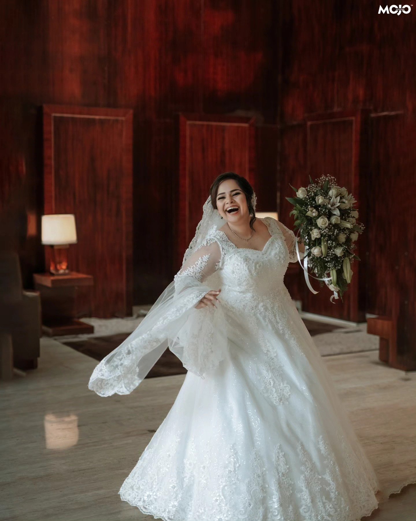 A joyful bride laughing with her bouquet